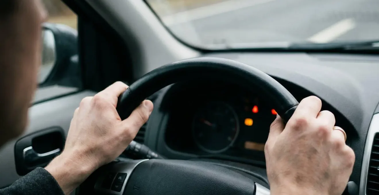 Gros plan dramatique sur une main au volant d'une voiture, illustrant la vulnérabilité du conducteur responsable face aux limites de la responsabilité civile automobile
