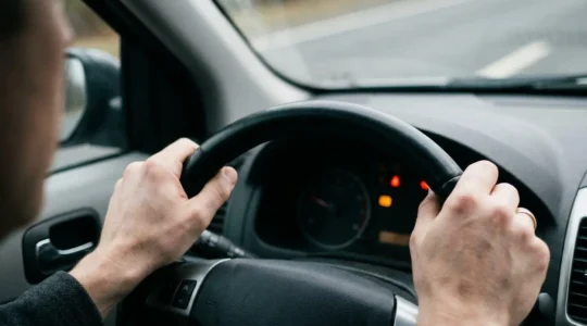 Gros plan dramatique sur une main au volant d'une voiture, illustrant la vulnérabilité du conducteur responsable face aux limites de la responsabilité civile automobile